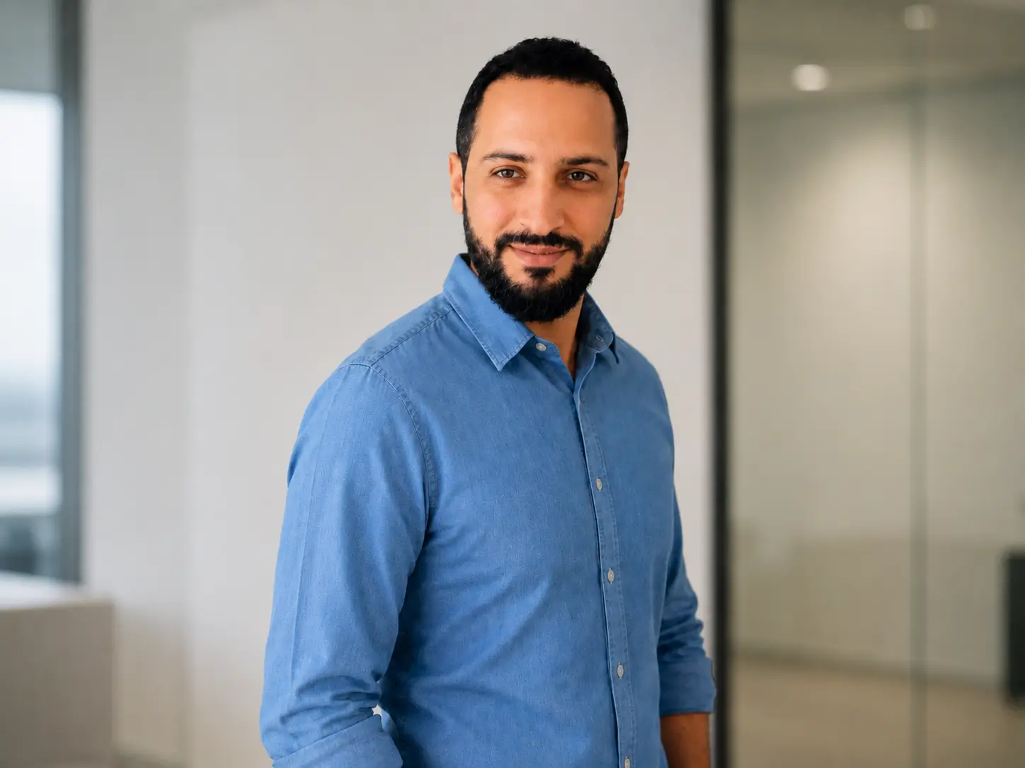 Guilherme Cazaroto seated at his desk beside a monitor displaying source code